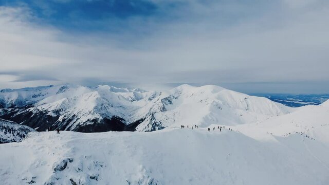 Aerial view of snow mountain range landscape in Zakopane under blue sky with winding road and sea of clouds in the background 4k winter drone 