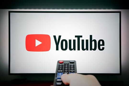 YouTube Logo On TV Screen. Remote Control In Hand