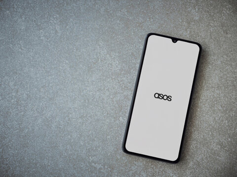 Lod, Israel - July 8, 2020: ASOS app launch screen with logo on the display of a black mobile smartphone on ceramic stone background. Top view flat lay with copy space.