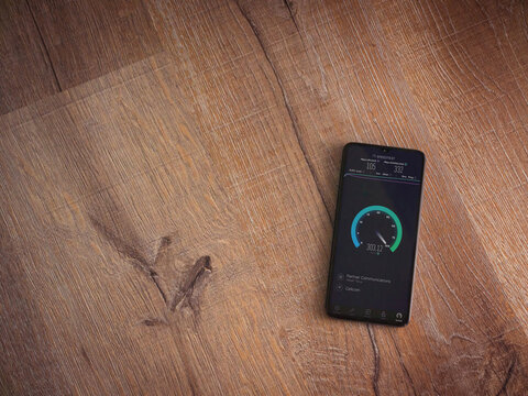 Lod, Israel - July 8, 2020: Speedtest app launch screen with logo on the display of a black mobile smartphone on wooden background. Top view flat lay with copy space.
