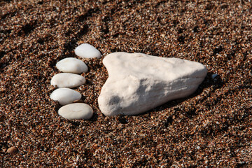 Fototapeta na wymiar Leg made of sea stones. White sea pebbles. Sea background.