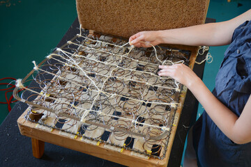 Woman fasten springs in upholstery workshop. Upholstery worker tying and sewing springs. Springs webbing, old chair restoration.