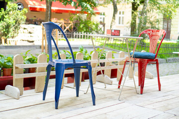 Restaurant outdoor seating. Red and blue chairs and white table in cafe. Summer empty outdoor cafe at european city