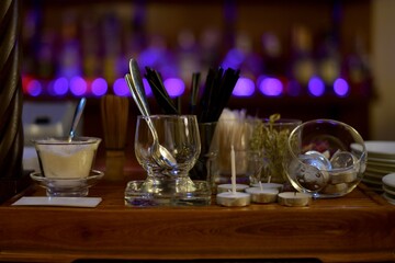 Bar stand with dishes, sugar, teaspoons, candles, tubes, skewers. Items serving.