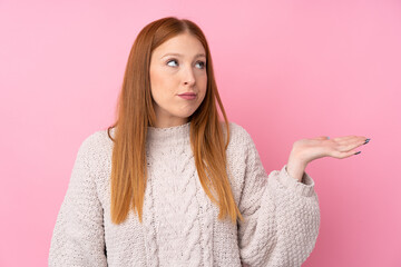 Young redhead woman over isolated pink background unhappy for not understand something
