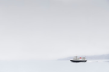 Lone ship ferry alone under dark grey sky and fog on ocean