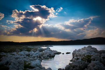 Atardecer sobre laguna en México, rayos del sol hermosos tras las nubes azules
