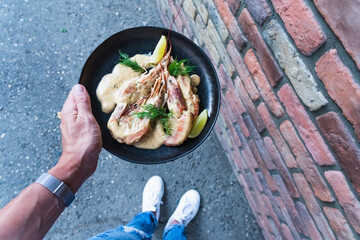 Delicious fried langoustines in sauce on a black plate, prepared in an Asian style. Fast and ready meal concept