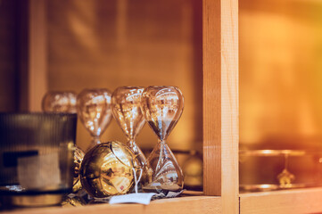 shiny transparent hourglasses on decoration shop shelf in golden light 