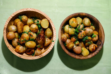 two wooden plates with fried whole new potatoes close up seasoned with herbs