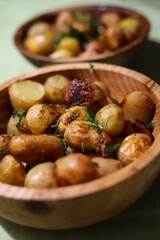 two wooden plates with fried whole new potatoes close up seasoned with herbs