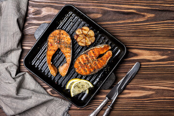 Spicy fried red fish salmon steak on grill pan with garlic and lemon