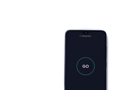 Lod, Israel - July 8, 2020: Speedtest app launch screen with logo on the display of a black mobile smartphone isolated on white background. Top view flat lay with copy space.