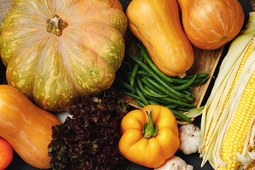 Autumn vegetable composition with pumpkin, corn and pepper on black background