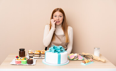 Obraz na płótnie Canvas Young redhead woman with a big cake nervous and scared