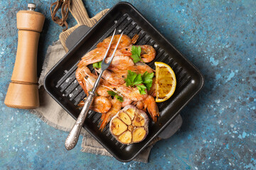 Spicy fried shrimps on grill pan with lemon, garlic and green parsley