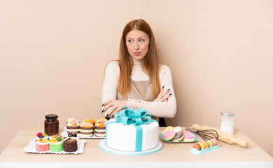 Obraz na płótnie Canvas Young redhead woman with a big cake thinking an idea