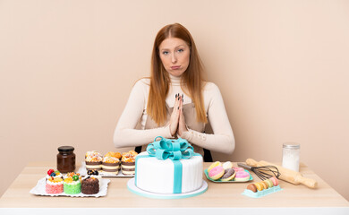 Obraz na płótnie Canvas Young redhead woman with a big cake pleading