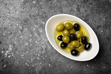 Bowl of delicious green and black olives in oil