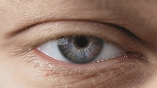 Close up shot of eye opening with beautiful blue iris. Healthy eyesight concept. Front view macro video in 4K