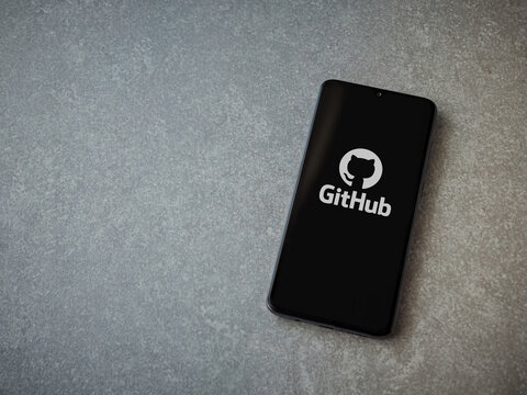 Lod, Israel - July 8, 2020: GitHub app launch screen with logo on the display of a black mobile smartphone on ceramic stone background. Top view flat lay with copy space.