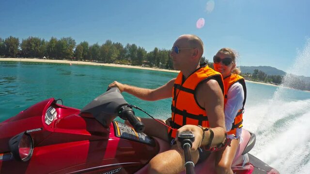 Happy smiling caucasian couple riding jet ski on sea