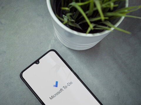 Lod, Israel - July 8, 2020: Modern minimalist office workspace with black mobile smartphone with Microsoft To Do app launch screen with logo on marble background. Top view flat lay with copy space.
