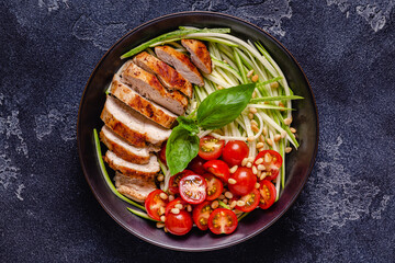 Fried chicken fillet and fresh vegetable salad of tomatoes, zucchini and pine nuts.