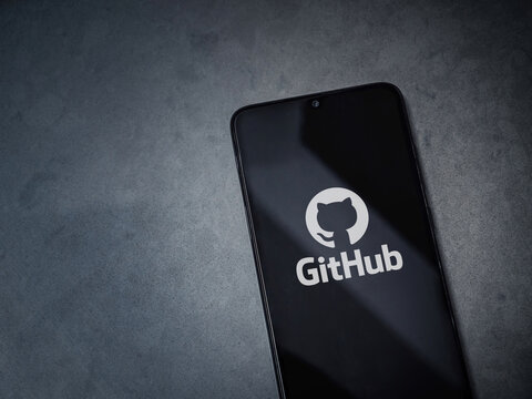 Lod, Israel - July 8, 2020: GitHub app launch screen with logo on the display of a black mobile smartphone on dark marble stone background. Top view flat lay with copy space.
