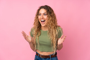 Young blonde woman with curly hair isolated on pink background with surprise facial expression