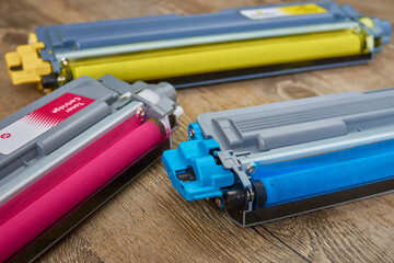 Yellow, cyan and magenta toner cartridges on wooden table