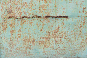 Old green metal sheathing sheet. There is rust on the surface and a line of perforating corrosion. Background. Texture.