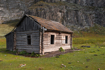 Beautiful wooden abandoned log house on mountains background