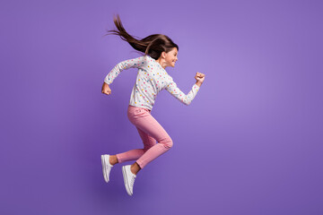 Fototapeta na wymiar Full length body size side profile photo of jumping high hurrying up preteen girl smiling isolated on vibrant violet color background