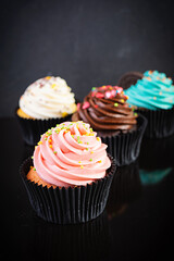 Tasty colorful cupcakes isolated on dark background. Delicious cupcake