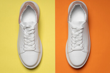 White leather sneakers on a yellow-orange background. A pair of trendy white athletic shoes or sneakers with copy space. flat lay