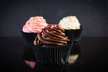 Tasty colorful cupcakes isolated on dark background. Delicious cupcake