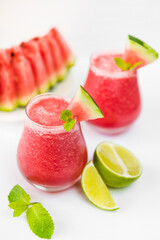 Watermelon smoothie in transparent glasses with mint leaf and lime on a light background