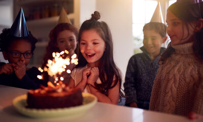 Girl Celebrating Birthday With Group Of Friends At Home Being Given Cake Decorated With Sparkler