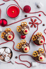 Christmas deer muffins on a white background decorated with red beads, a candle and Christmas decorations