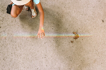 Touching rainbow. Good times are coming. A girl holding her hand under rainbow.