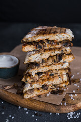 Vegan panini with mushrooms and caramelized onions on a wooden board on a dark background with sauce