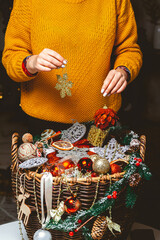 Young Woman with a Box Choosing Christmas Decorations in a Basket