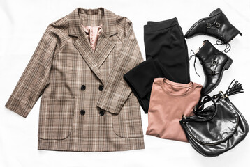 Set of women's fashion clothing - plaid jacket, black trousers, t-shirt, leather shoes and bag on a...