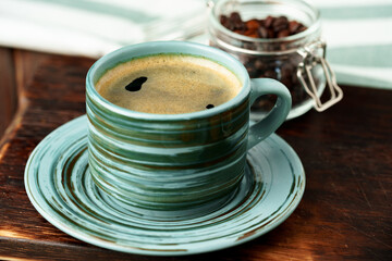 Green cup of coffee on saucer on wooden table