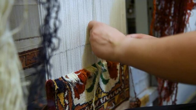 woman hands knitting carpet on a loom