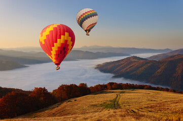 Two hot air balloons fly over the mystical foggy Carpathian mountains