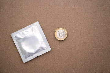 Euro is next to the condom. European union money lies on a textured table with condom.