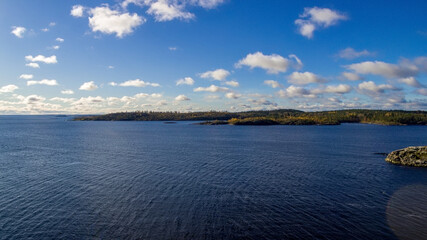 Top view of several small stone islands located in the middle of the water of Lake Ladoga, on a sunny day with a few clouds