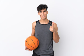 Obraz premium Young Argentinian man over isolated white background playing basketball and with thumb up